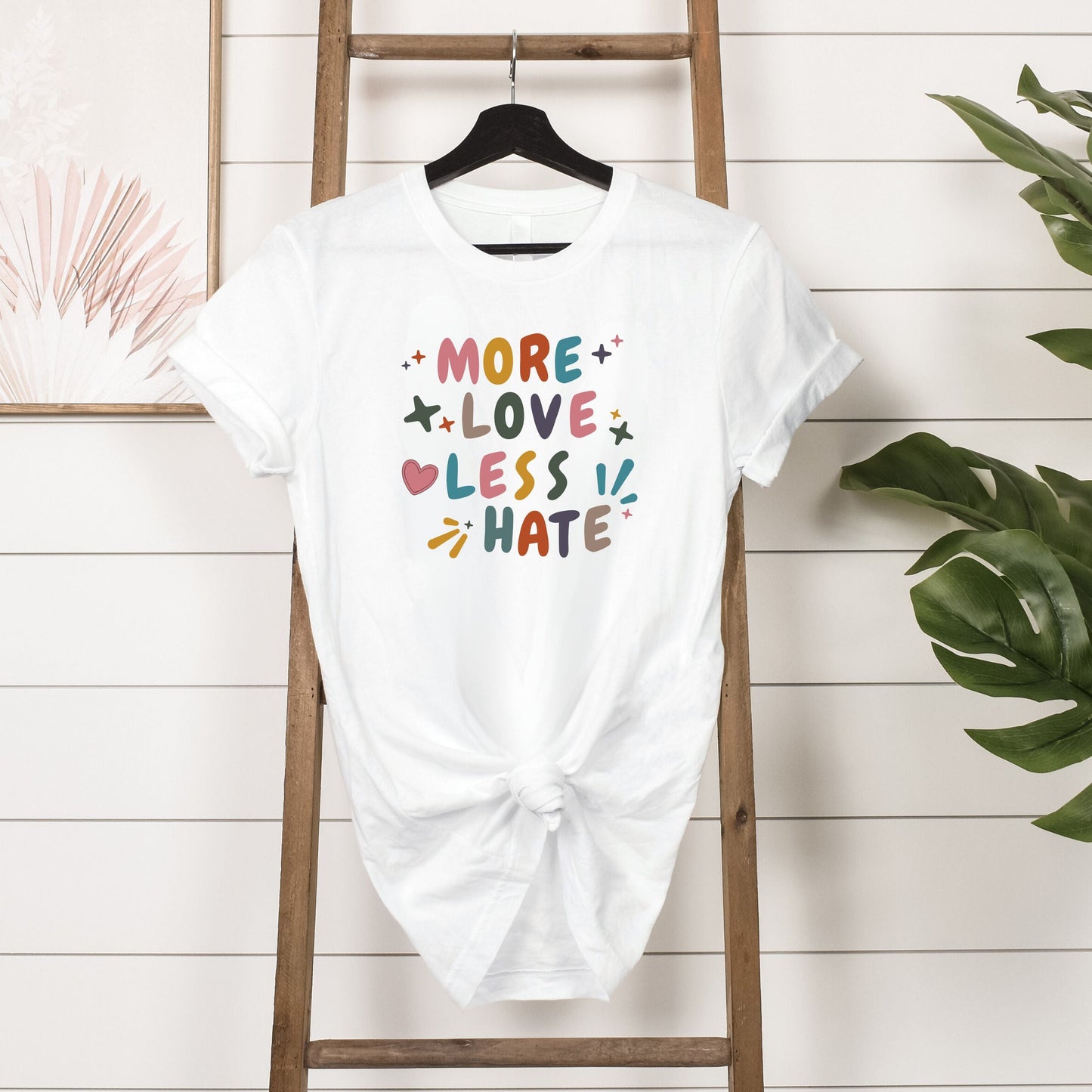 More Love Less Hate T-Shirt Hanging in White 